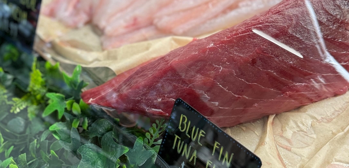 Premium bluefin tuna fillets on ice with label at Makai Seafood Market, highlighting freshness and color.