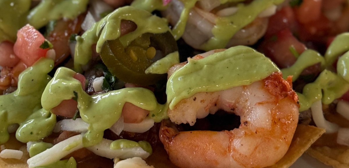Crispy tortilla chips topped with shrimp, avocado sauce, and pico de gallo at Makai Seafood Market.